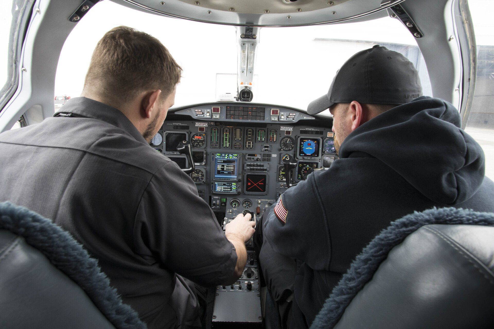 Two men are sitting in the cockpit of an airplane