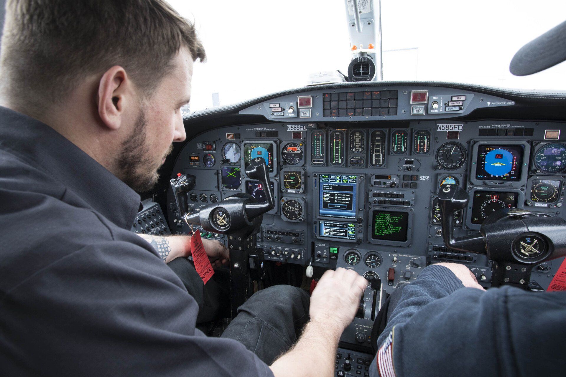 Two men are sitting in the cockpit of an airplane.