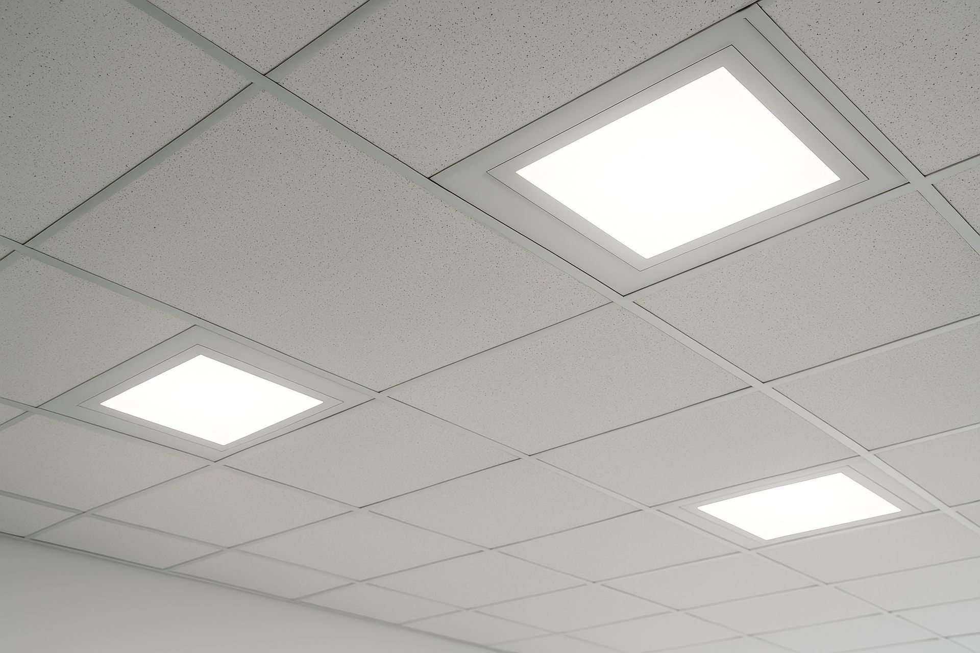 White textured ceiling tiles with three illuminated square LED lights.