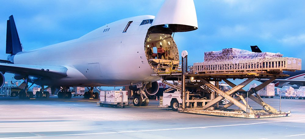 Cargo plane loading a military vehicle onto a ramp at an airfield