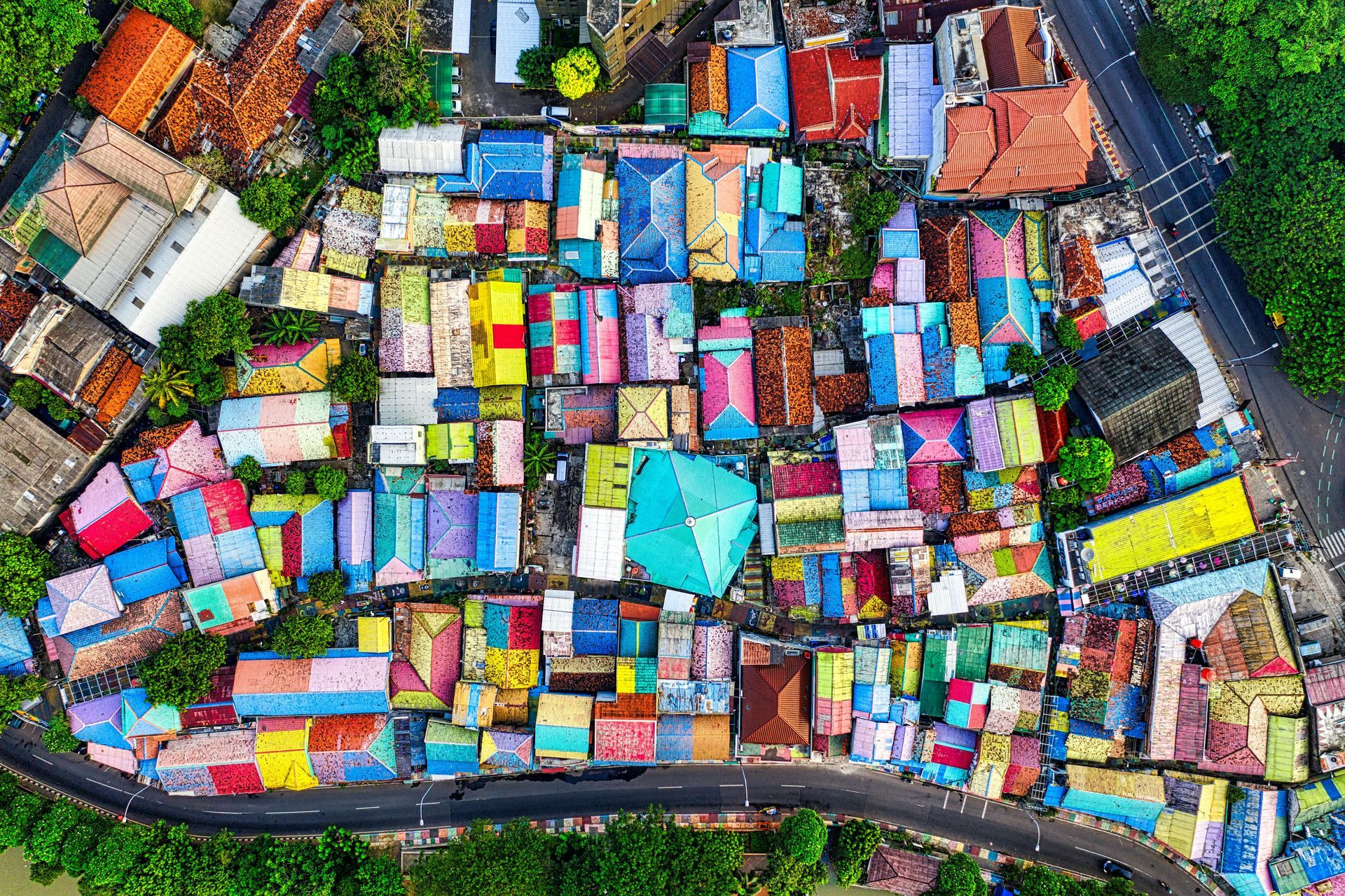 Aerial view of a dense colorful market or settlement with many small rooftops and narrow paths.