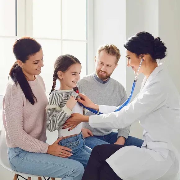 Doctor examining a child’s chest while parents look on in a bright clinic room