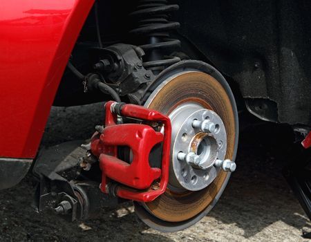 Red car wheel with exposed brake rotor and bright red caliper close-up