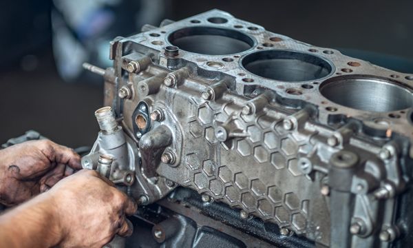 Mechanic working on a metal engine block in a workshop