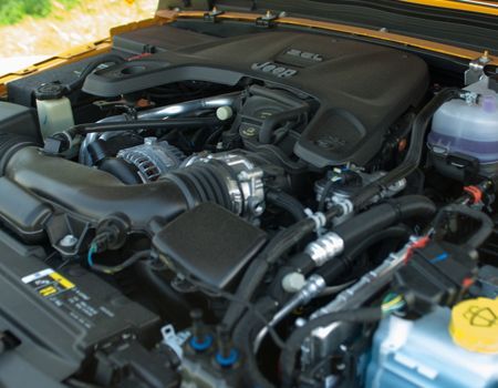 Open car hood showing a clean engine bay with black components and a yellow fluid cap