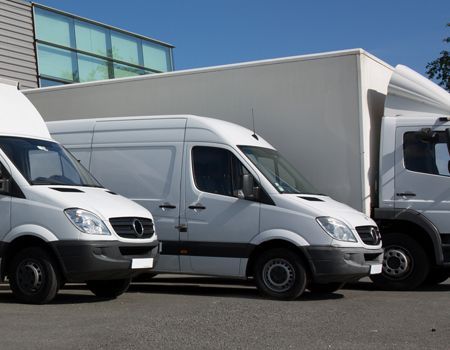 White delivery vans parked outside a warehouse on a sunny day