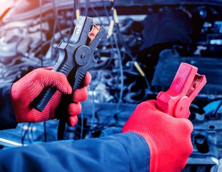 Gloved hands using a wire stripper and electrical connector in an engine bay