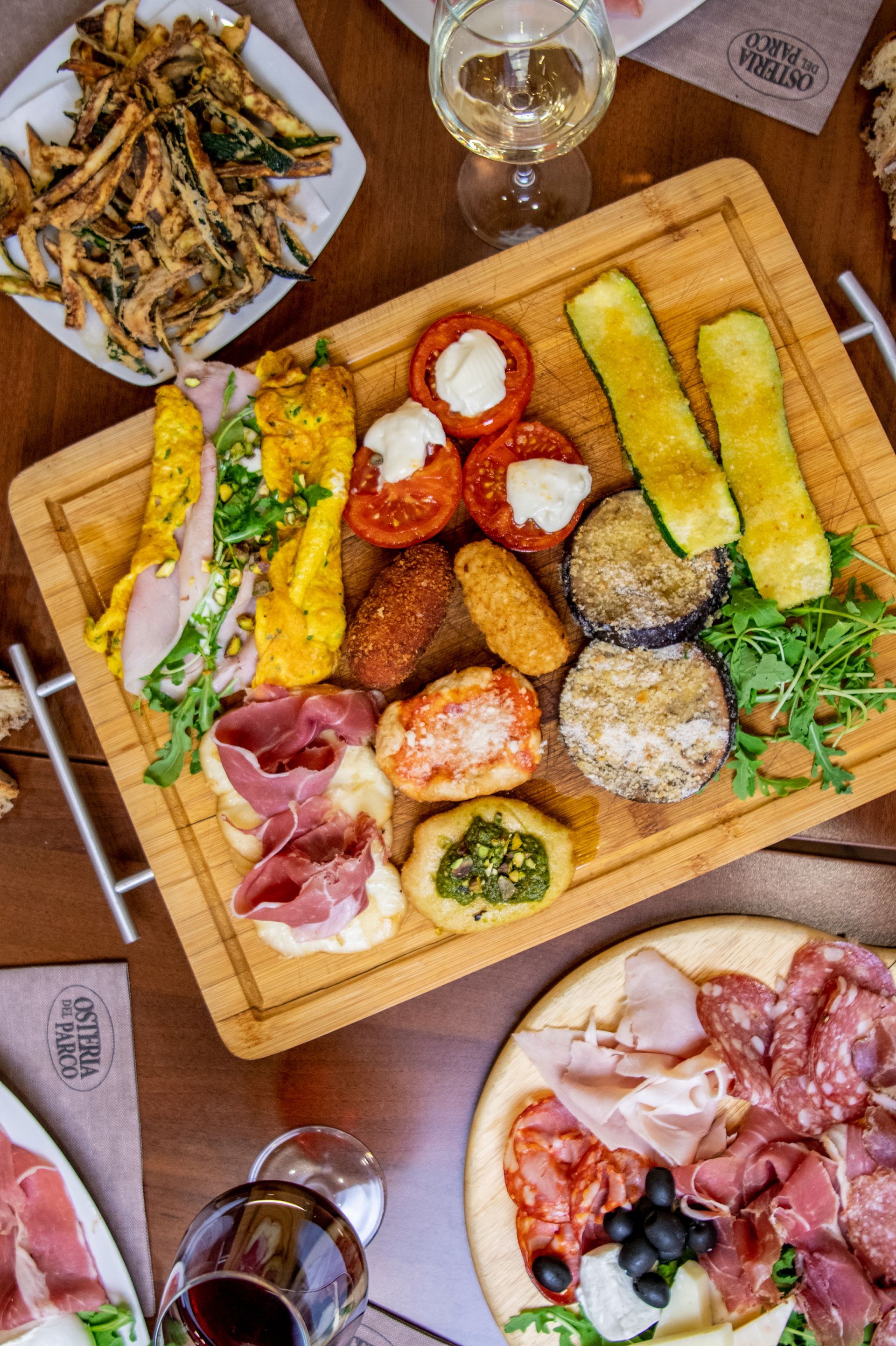 Tagliere di legno per salumi con formaggi, salumi, cracker e sottaceti su un tavolo di ristorante.
