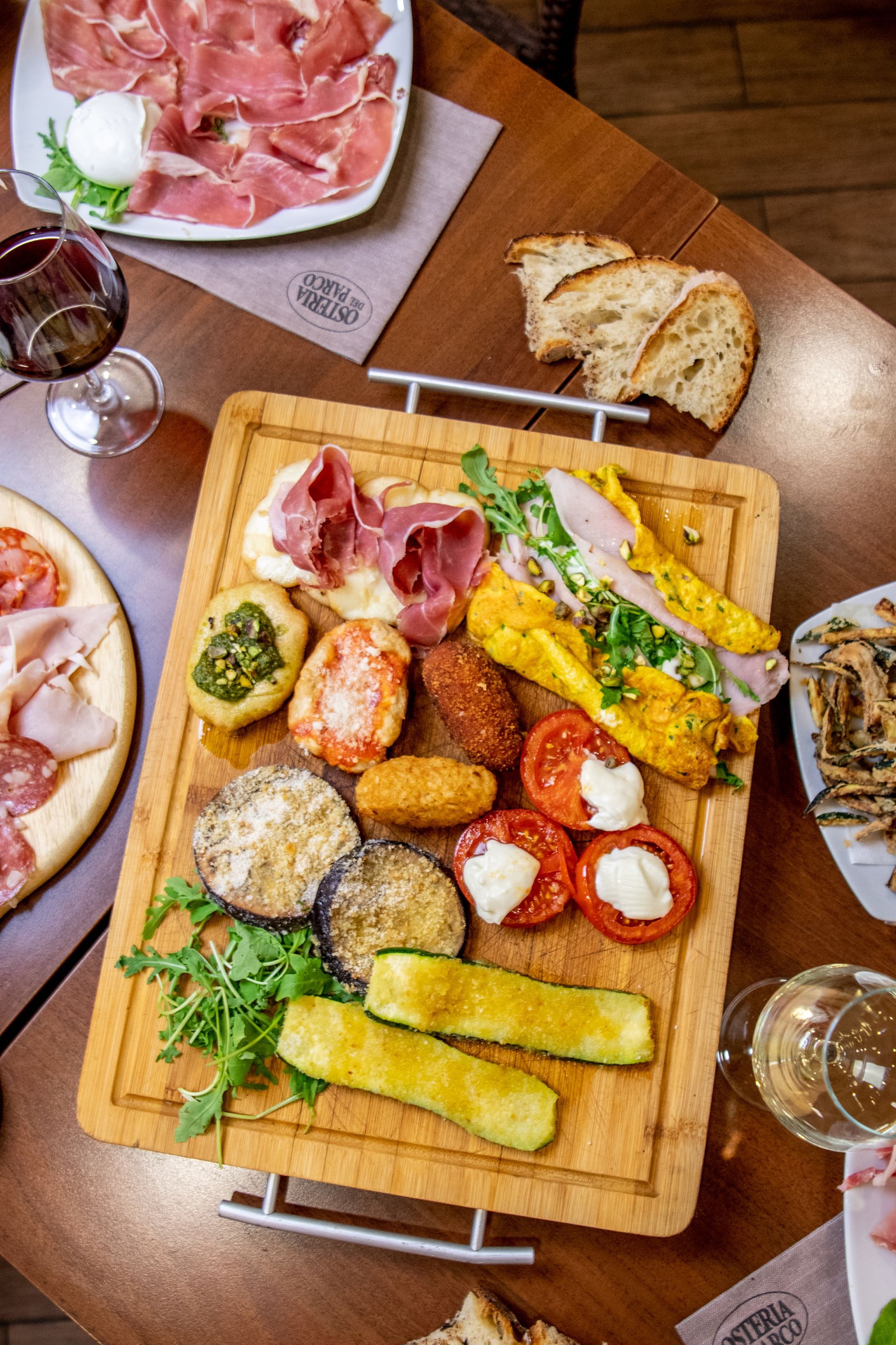 Tagliere di salumi, formaggi, pane e frutta su un tavolo da pranzo con bevande