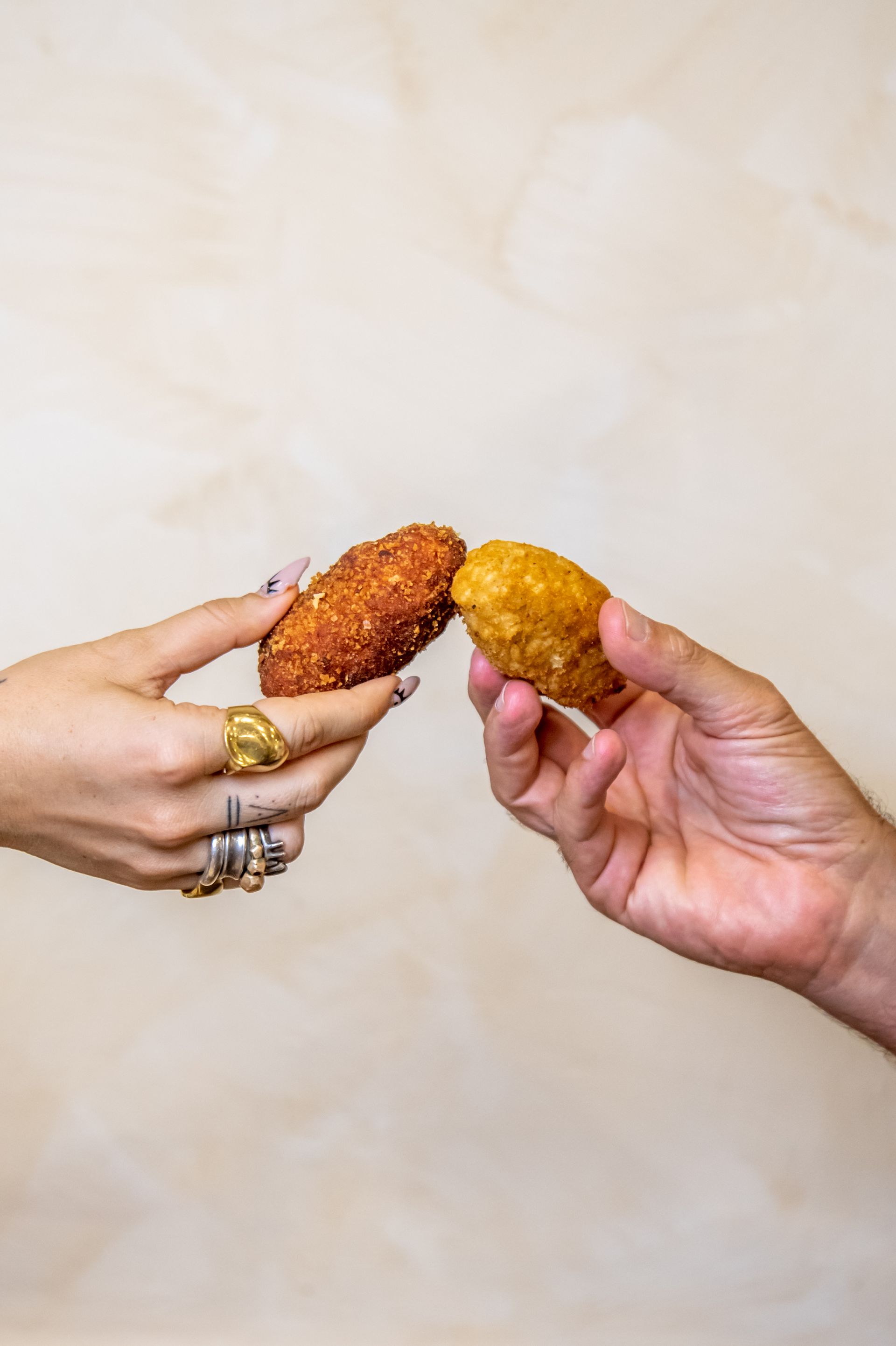 Due mani che reggono uno snack croccante marrone e uno snack giallo su uno sfondo chiaro