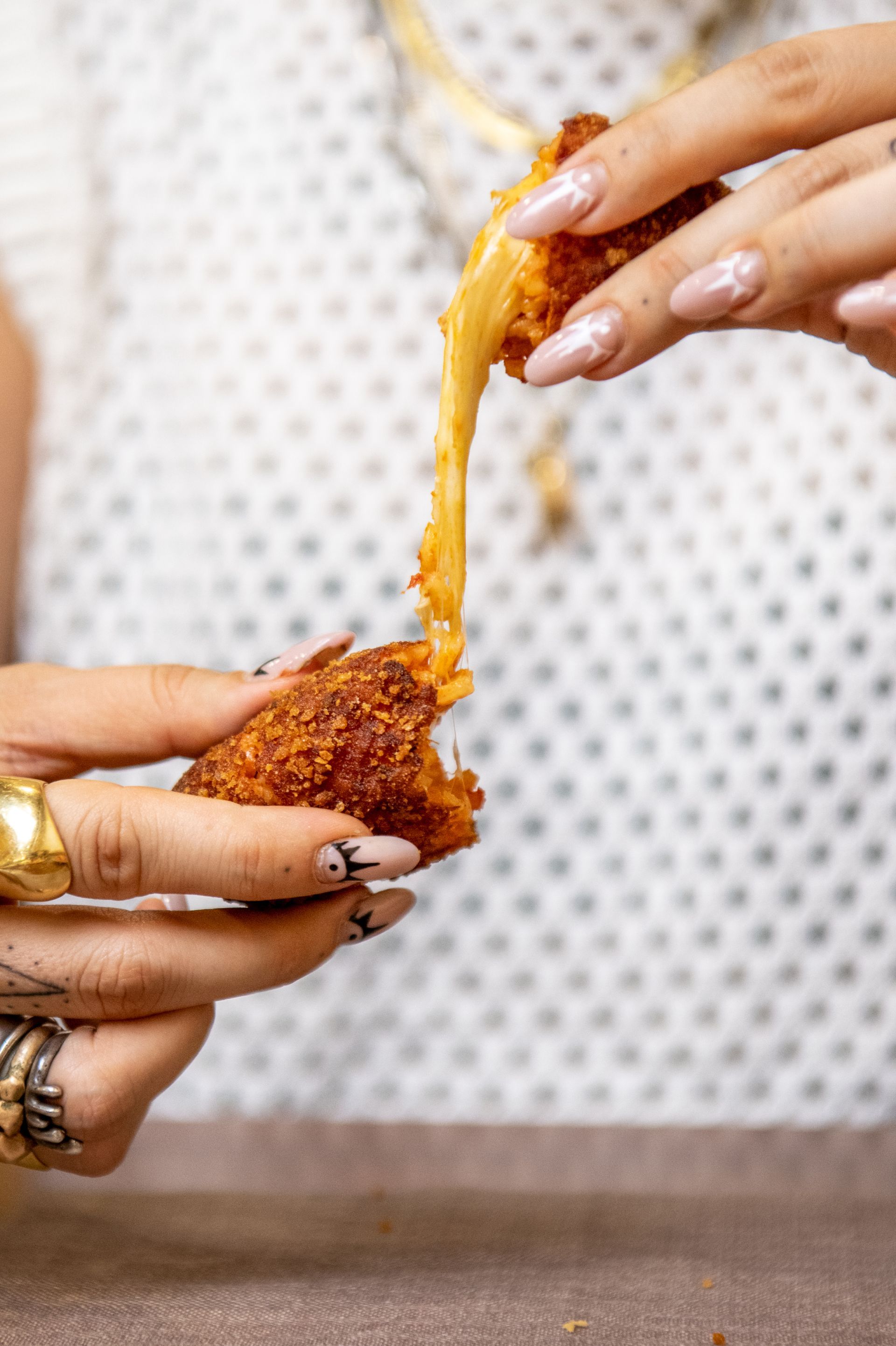Mani che separano uno snack fritto al formaggio su un tavolo