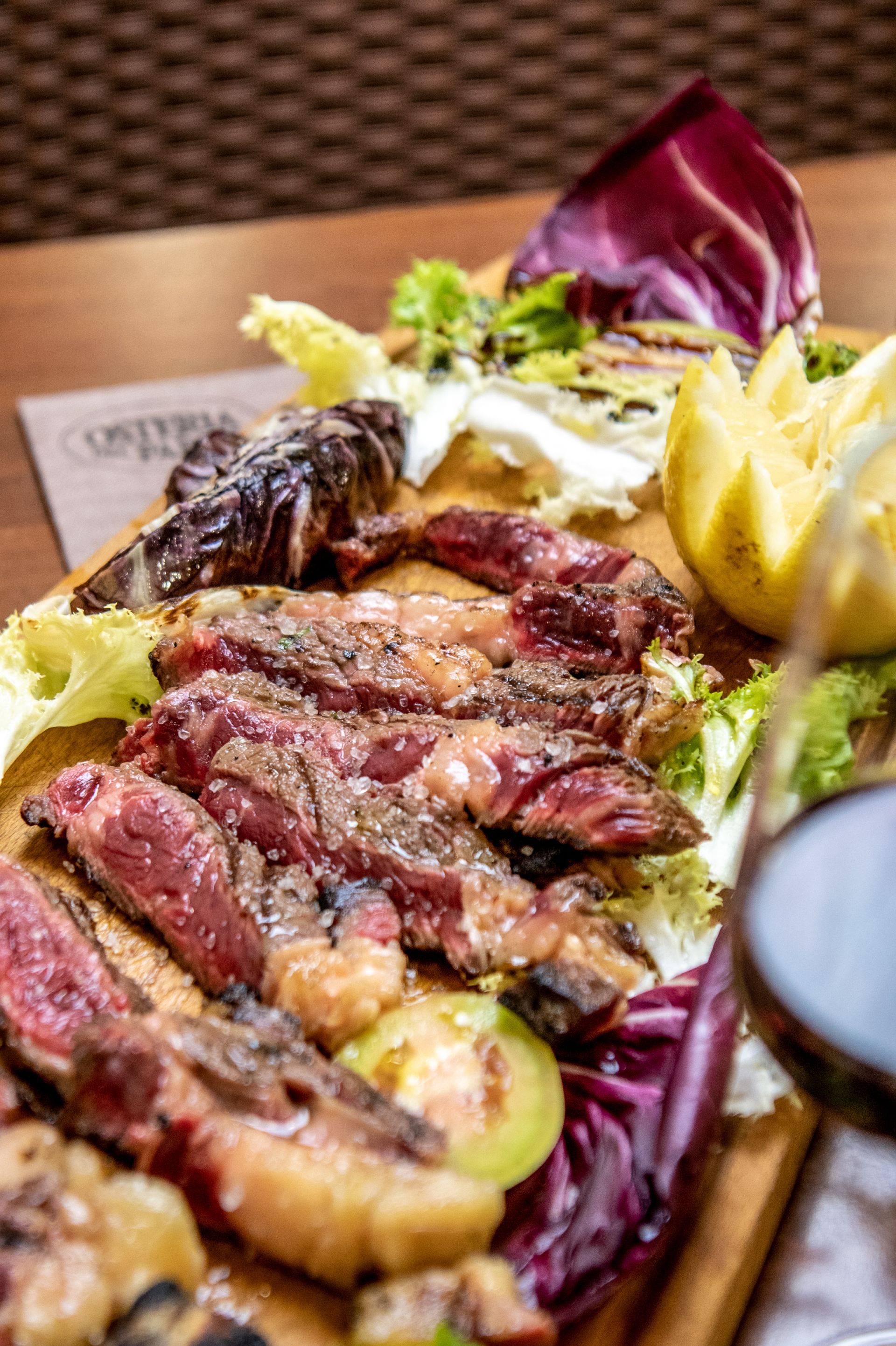Fettine di bistecca grigliate con spicchi di limone e verdure su un piatto in un ristorante