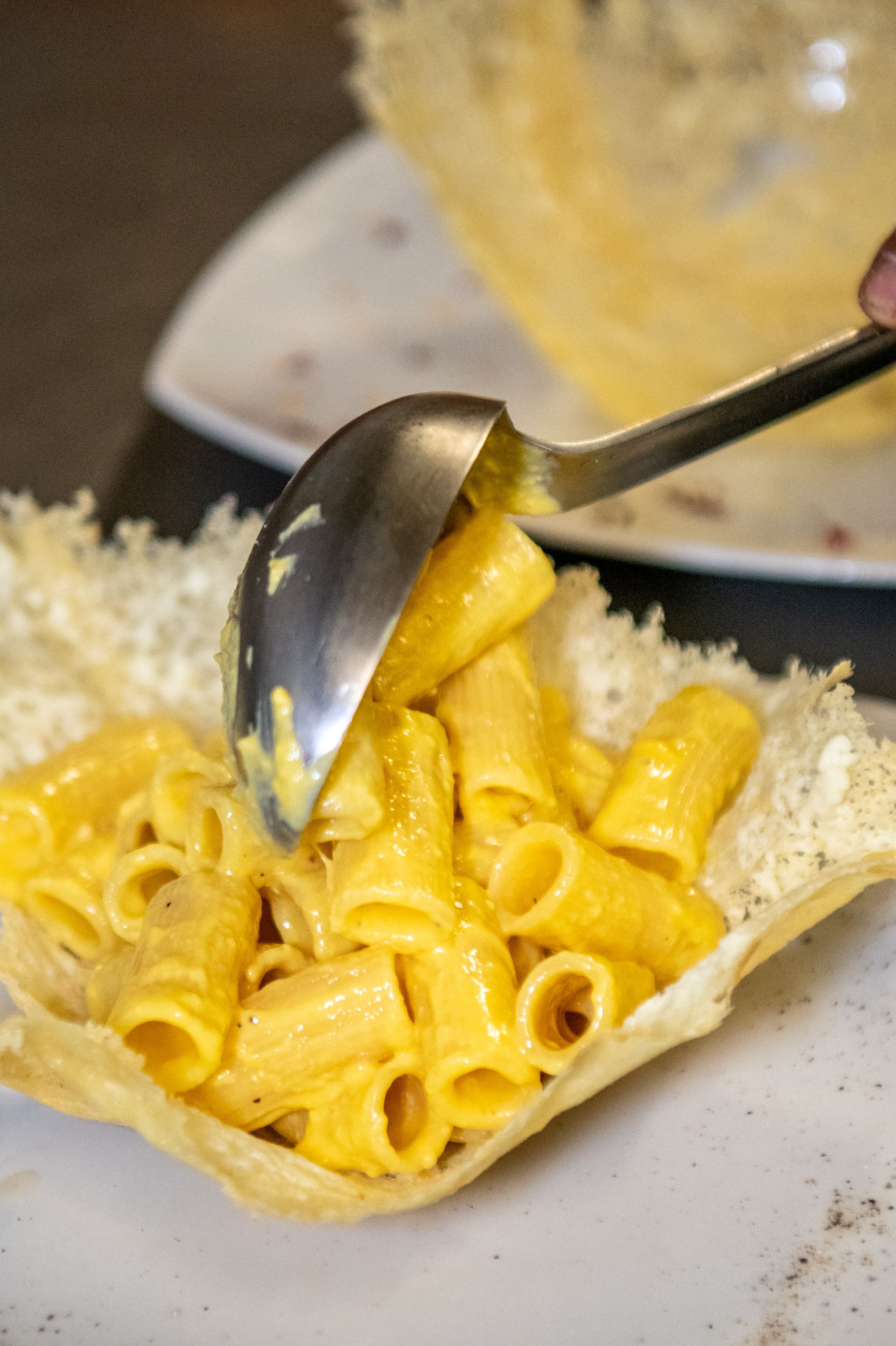 Maccheroni al formaggio raccolti in una ciotola di pane croccante con un cucchiaio.