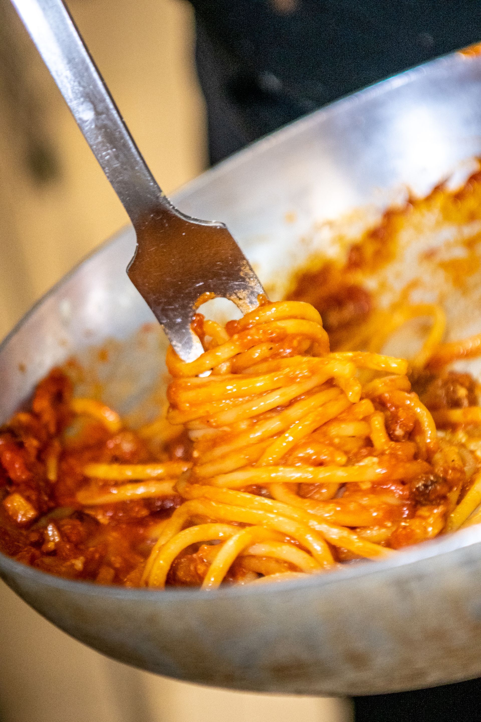 Spaghetti al sugo di pomodoro arrotolati con la forchetta sopra una ciotola di metallo