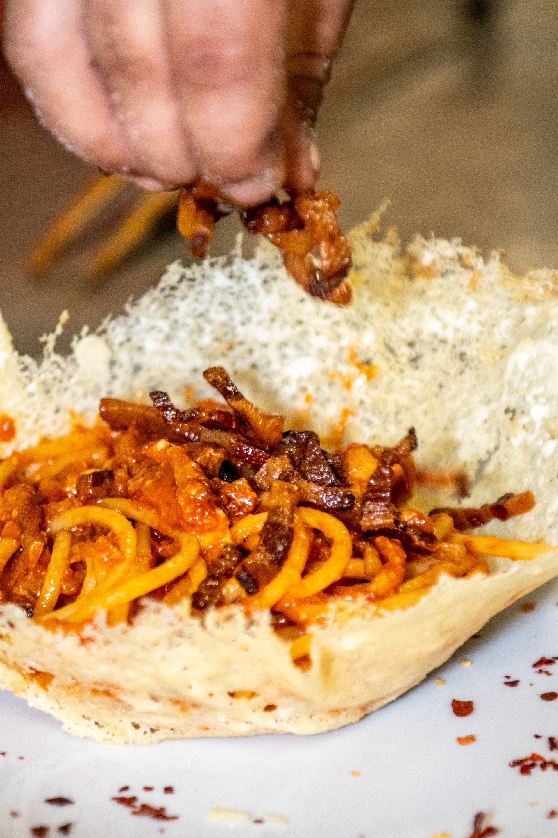 Aggiungere manualmente i noodles conditi con salsa a un panino di pane bianco su un piatto