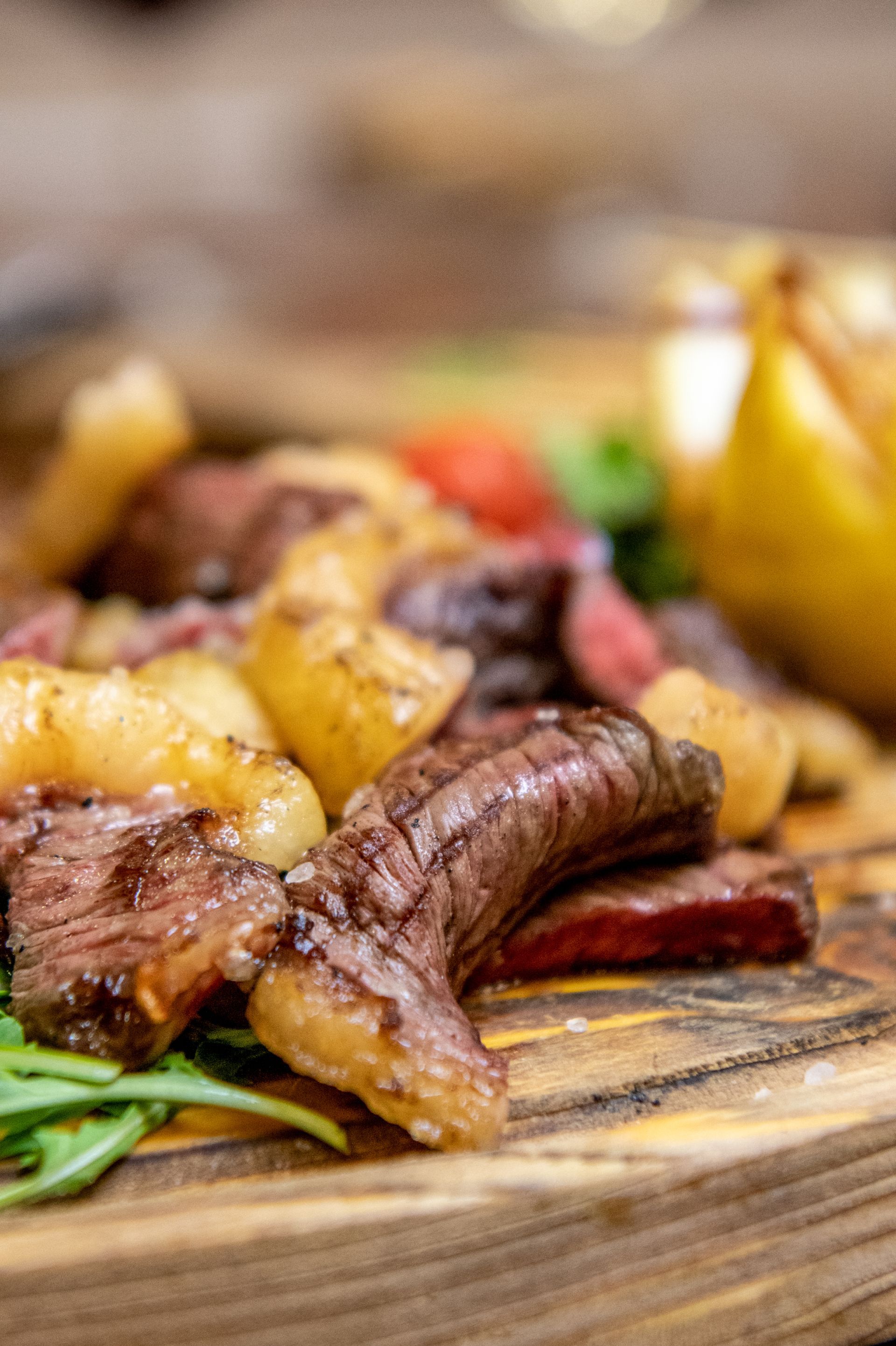 Bistecca alla griglia con patate arrosto su un tagliere di legno, guarnita con verdure