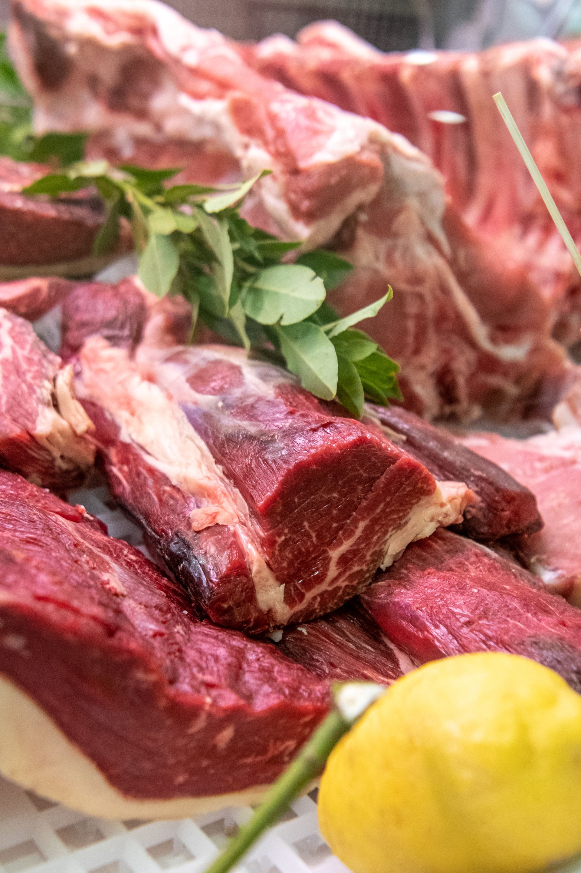 Tagli di manzo crudo con erbe aromatiche e un limone su un tavolo