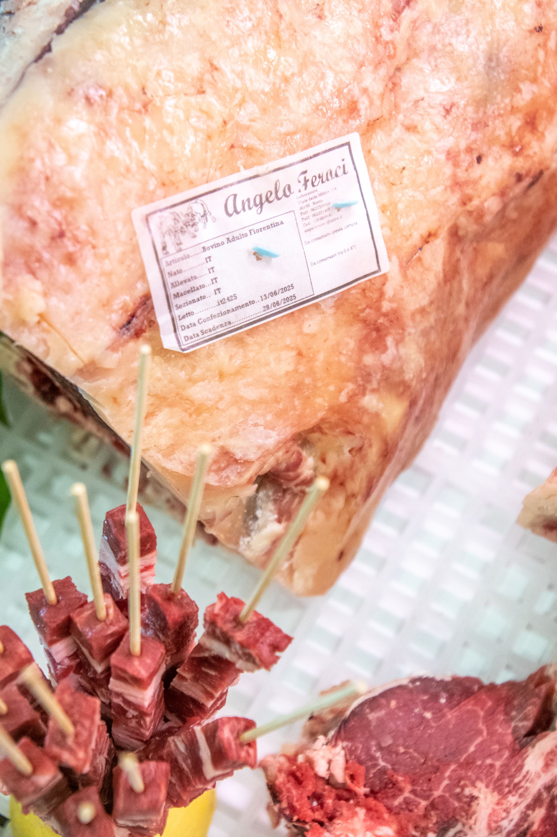 Primo piano di prosciutto crudo con etichetta e cubetti di carne infilzati su uno spiedino su un vassoio da portata.