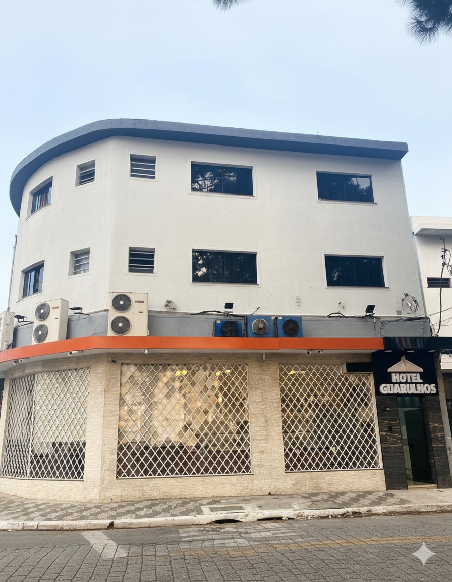 Prédio de hotel com fachada curva; paredes brancas, detalhes em laranja, lojas no térreo e céu nublado.