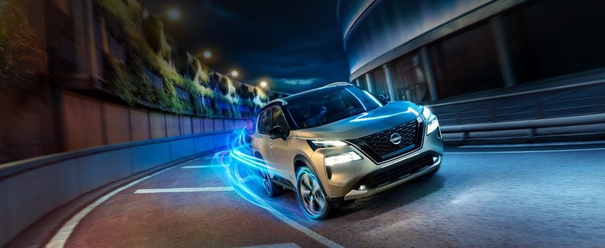 Un SUV plateado a toda velocidad atraviesa un túnel curvo con estelas azules de movimiento por la noche.