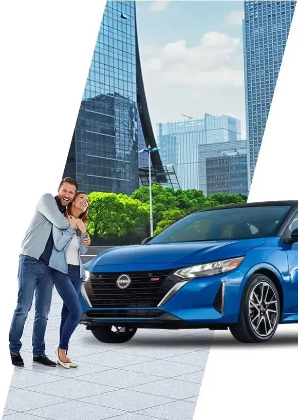 Pareja feliz posando junto a un sedán Nissan azul en una moderna plaza urbana con rascacielos.