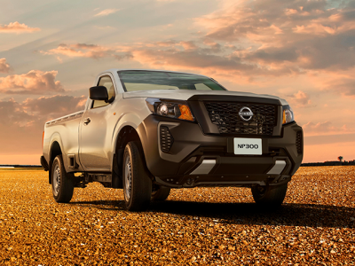 Camioneta Nissan blanca estacionada en una llanura de grava bajo un cálido cielo de atardecer.
