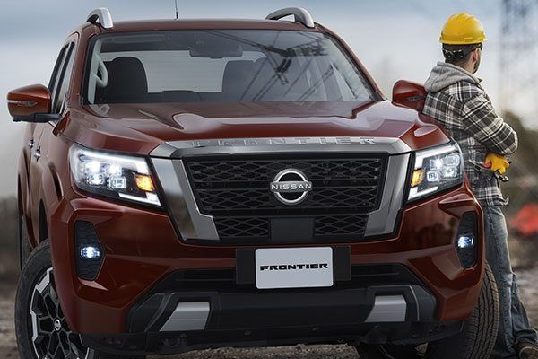 Camioneta Nissan color granate en una carretera con niebla, con un trabajador con casco amarillo a su lado.