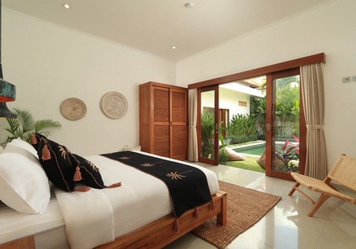Bedroom with a wooden bed, wardrobe, and sliding doors opening to a pool area.