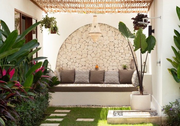 Outdoor seating area with stone wall, built-in bench, plants, and bamboo ceiling.