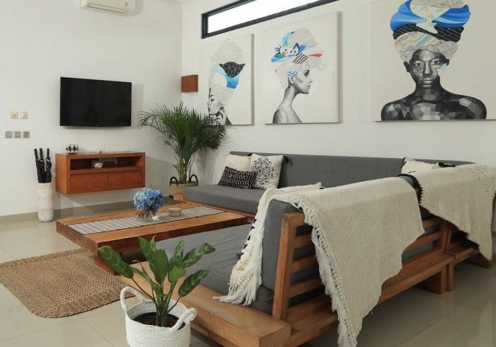 Living room with gray sofa, wooden furniture, artwork, and plants.