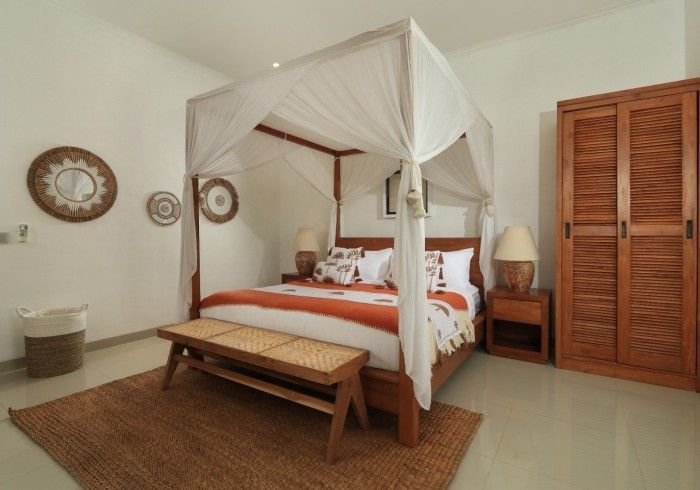 Bedroom with a four-poster bed, wood furniture, neutral tones, and decorative wall hangings.