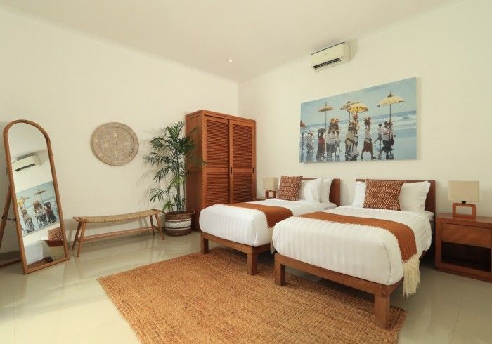 Bedroom with two twin beds, wooden furniture, artwork, and neutral tones.