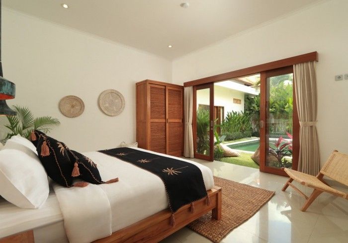 Bedroom with wooden furniture, bed, wardrobe, sliding doors open to a pool and garden.