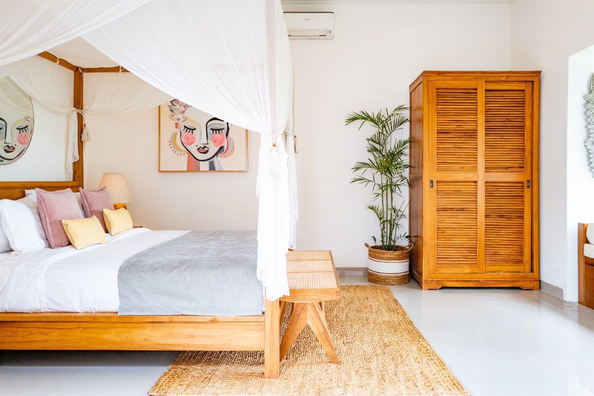 Bedroom with wooden furniture, canopy bed, artwork, and woven rug.