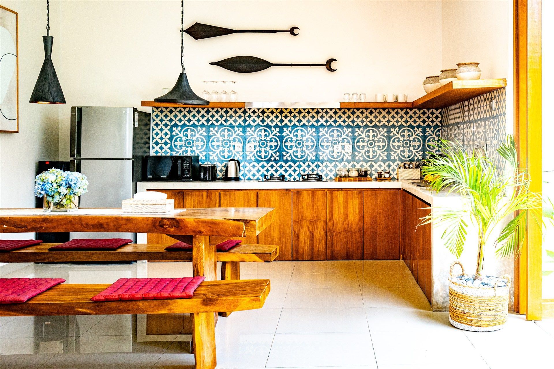 Kitchen with wooden cabinets, blue tile backsplash, stainless steel appliances, and a rustic wooden table and benches.