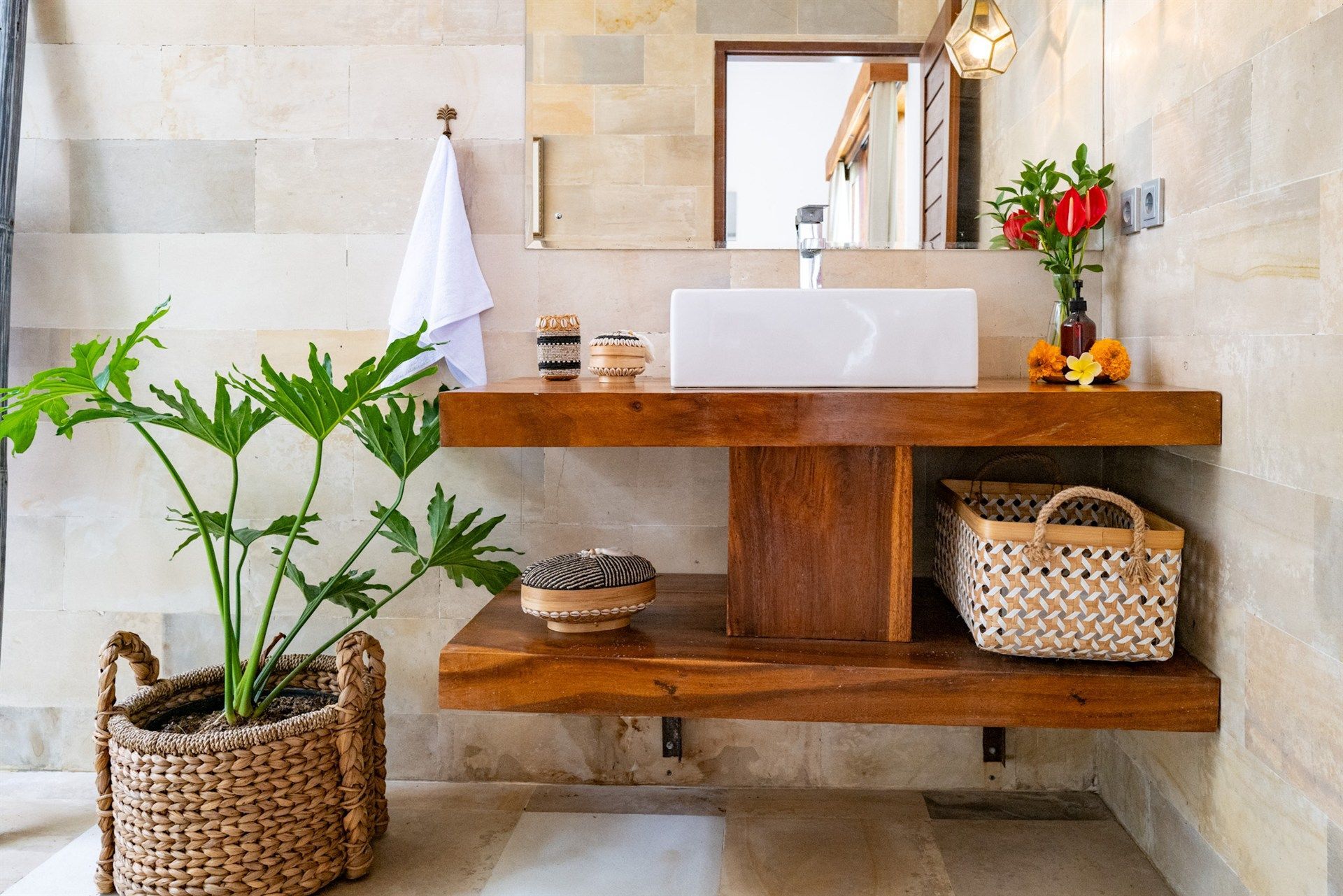 Bathroom with a floating wooden vanity, white vessel sink, and potted plant, featuring a neutral color palette.