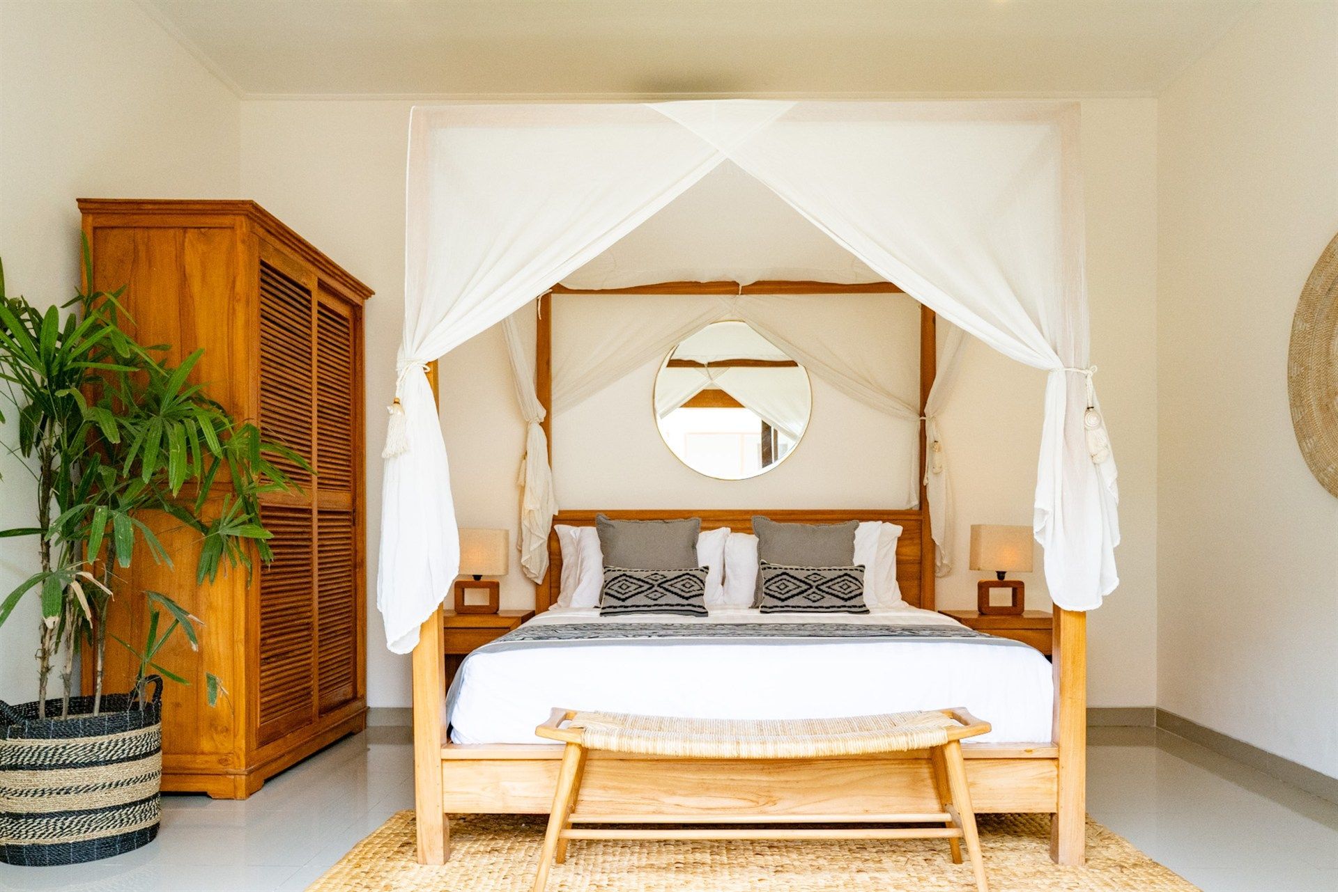 Bedroom with canopy bed, wooden wardrobe, indoor plant, and woven rug.