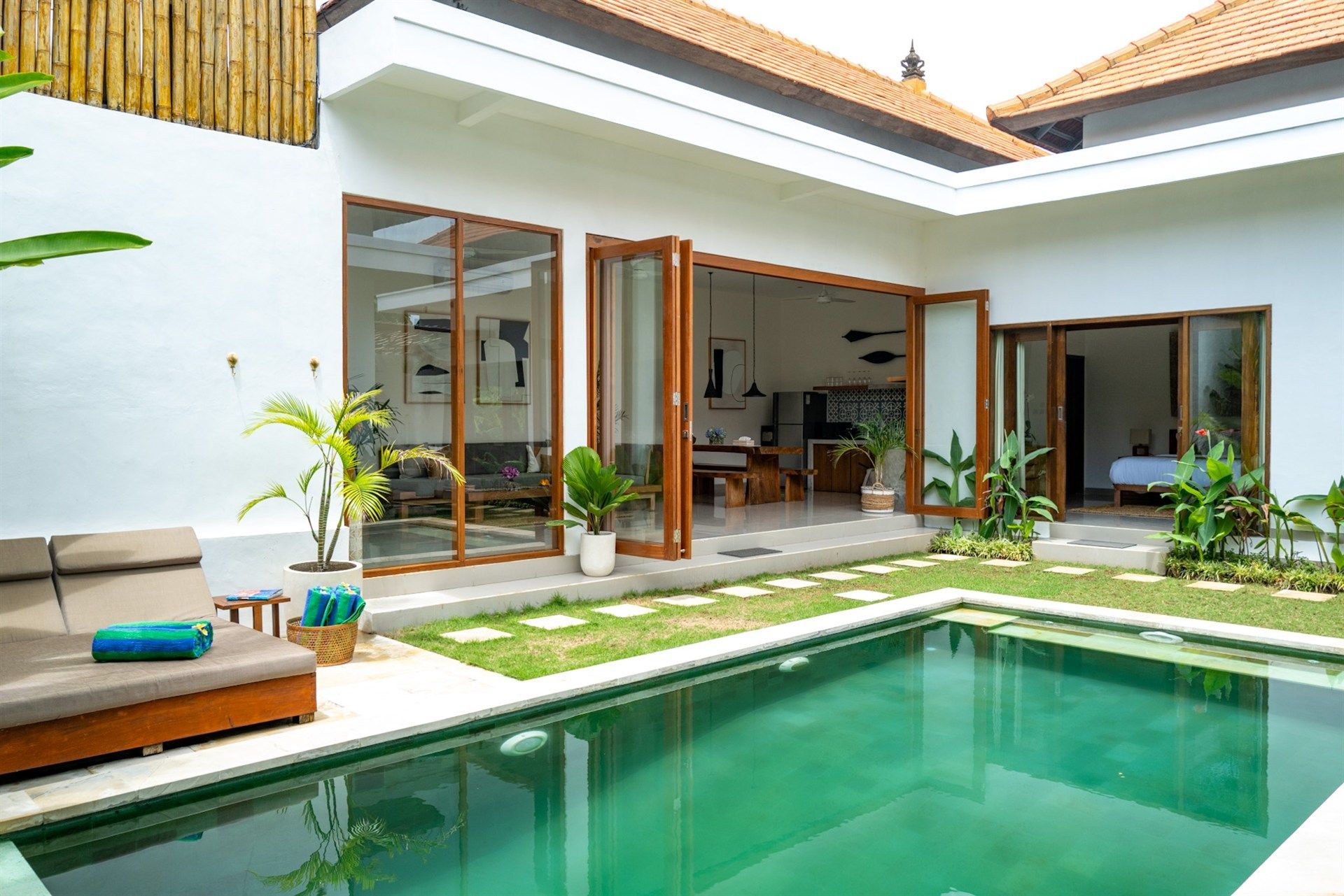 A courtyard villa with a pool, open doors, and outdoor seating.