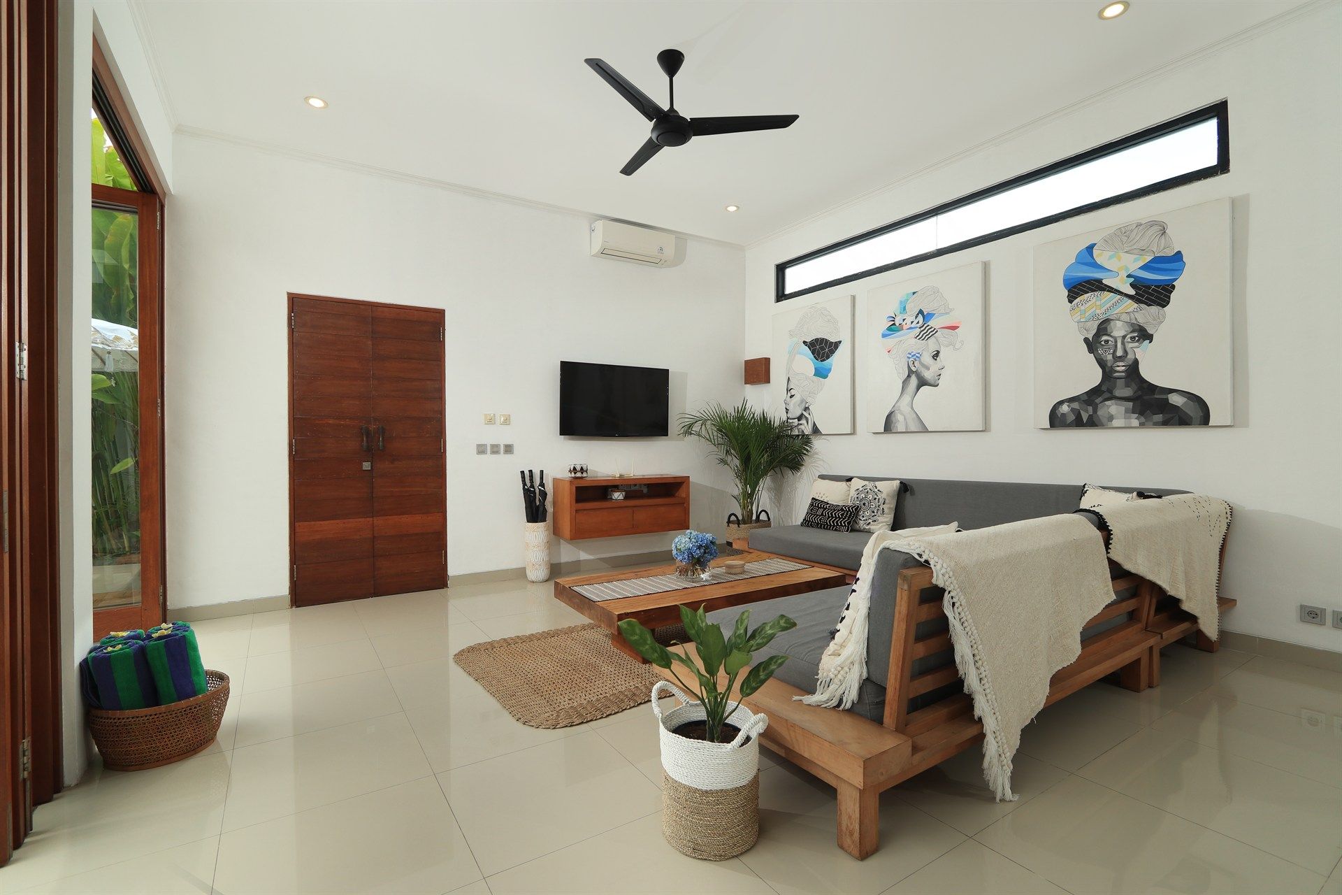 Living room with gray sofa, wooden furniture, and three framed art pieces on a white wall.