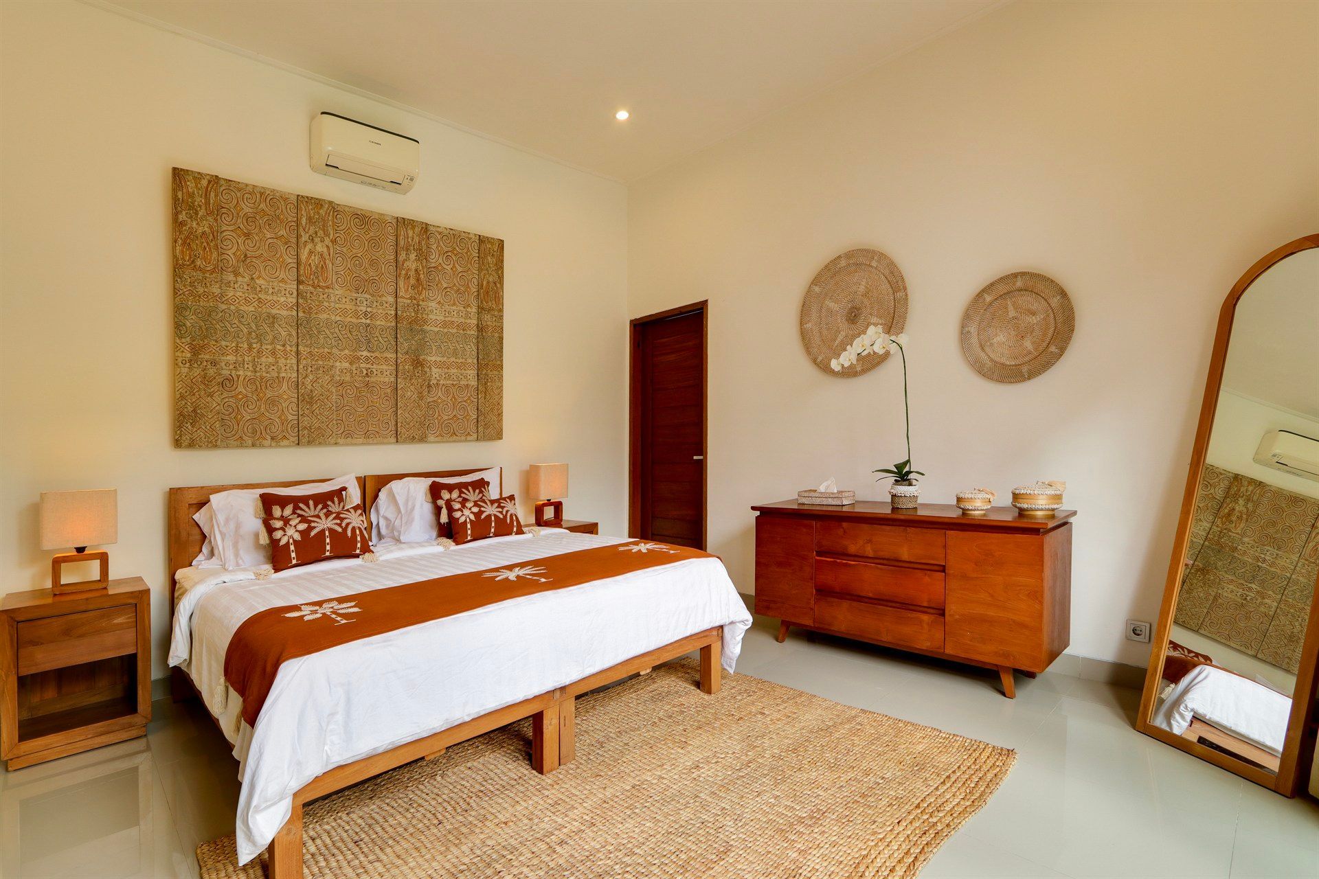 Bedroom with wooden furniture, large bed, jute rug, and decorative wall art.