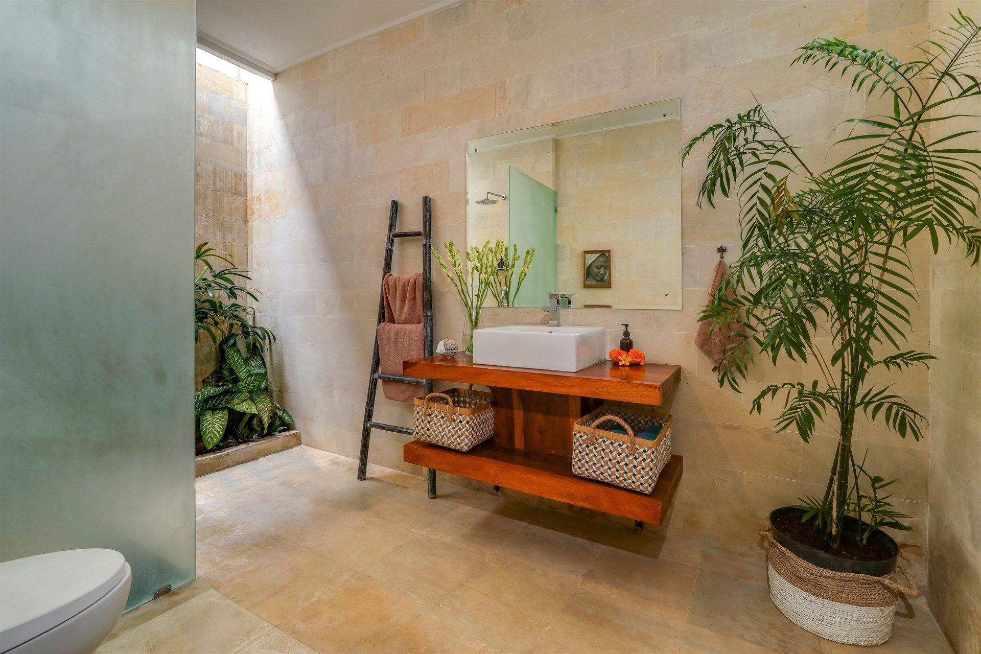 Bathroom with natural light, wood vanity, plants, and a frosted glass shower enclosure.