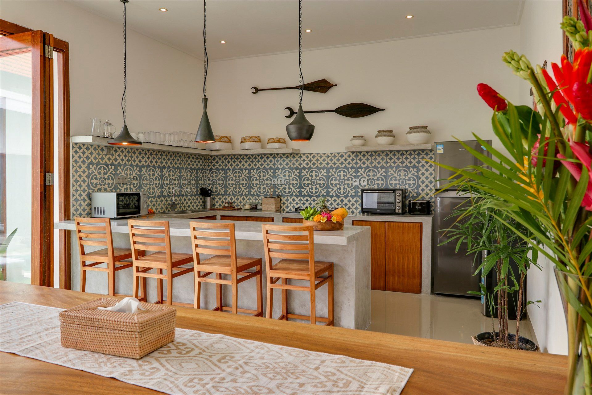 Modern kitchen with a breakfast bar, wooden chairs, and decorative tile backsplash.