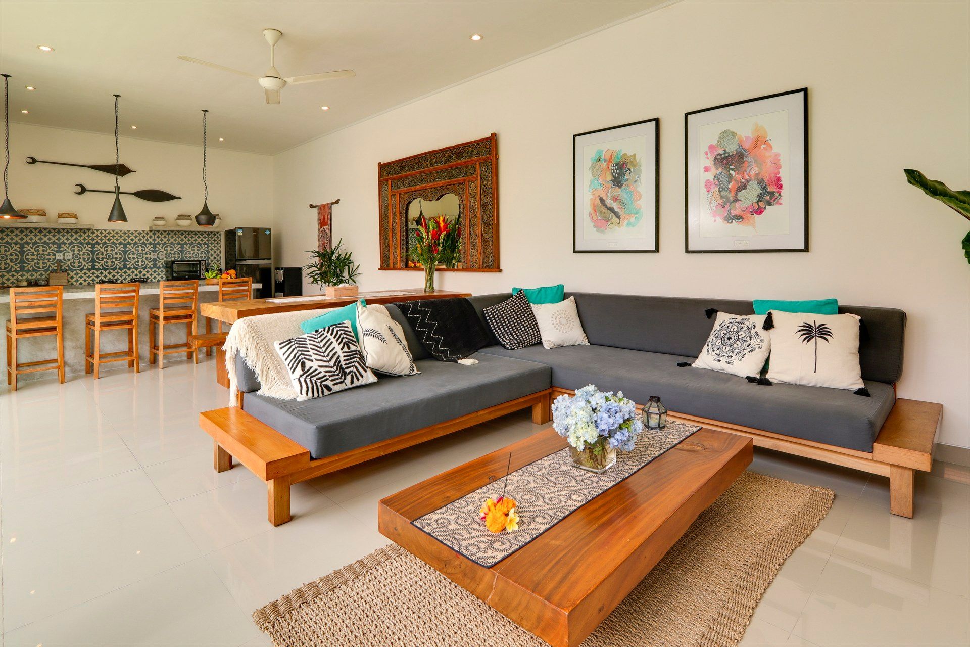 Open-plan living space with grey sectional sofa, wooden coffee table, and kitchen area with bar seating.