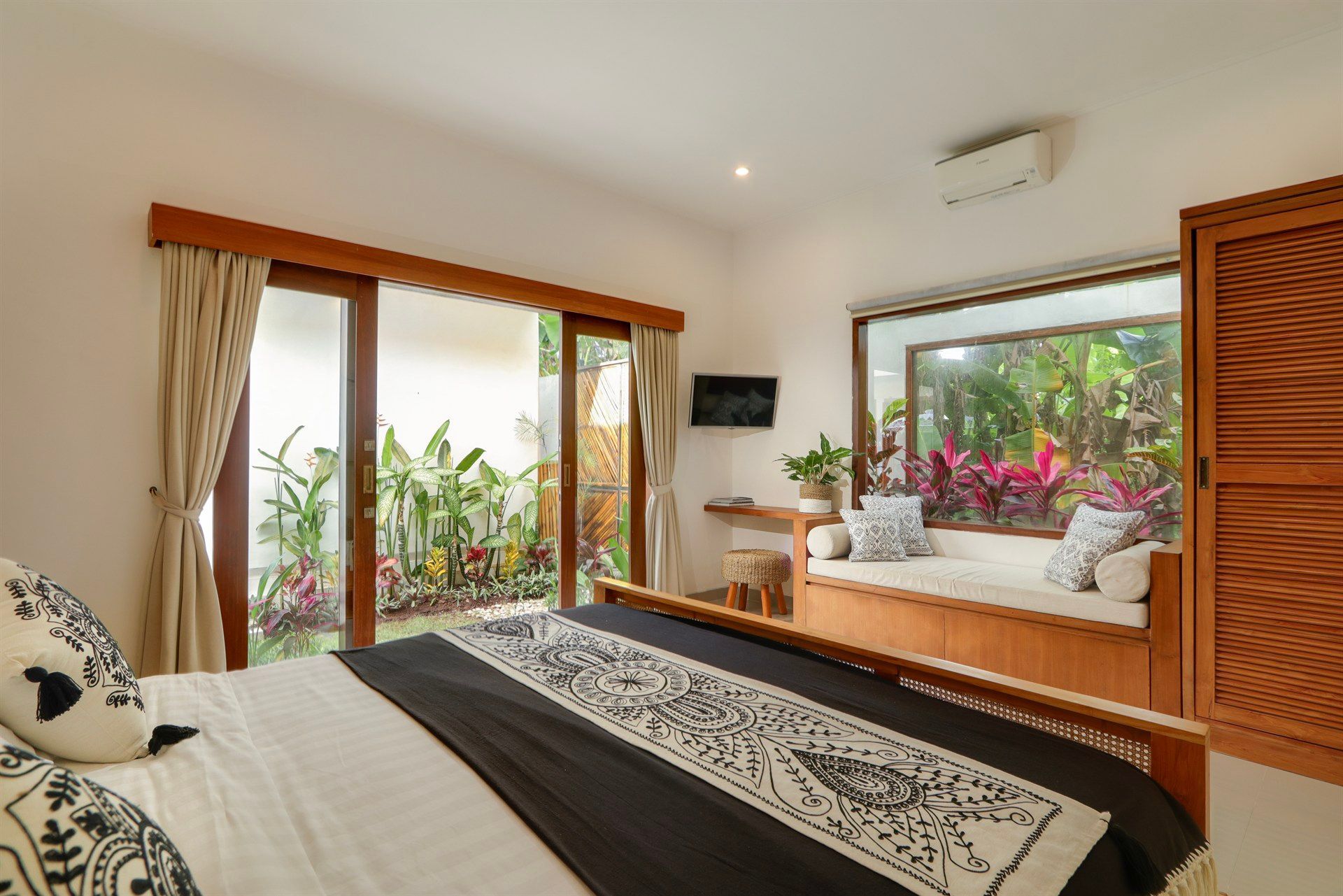Bedroom with bed, garden view, built-in window seat, and wooden accents.