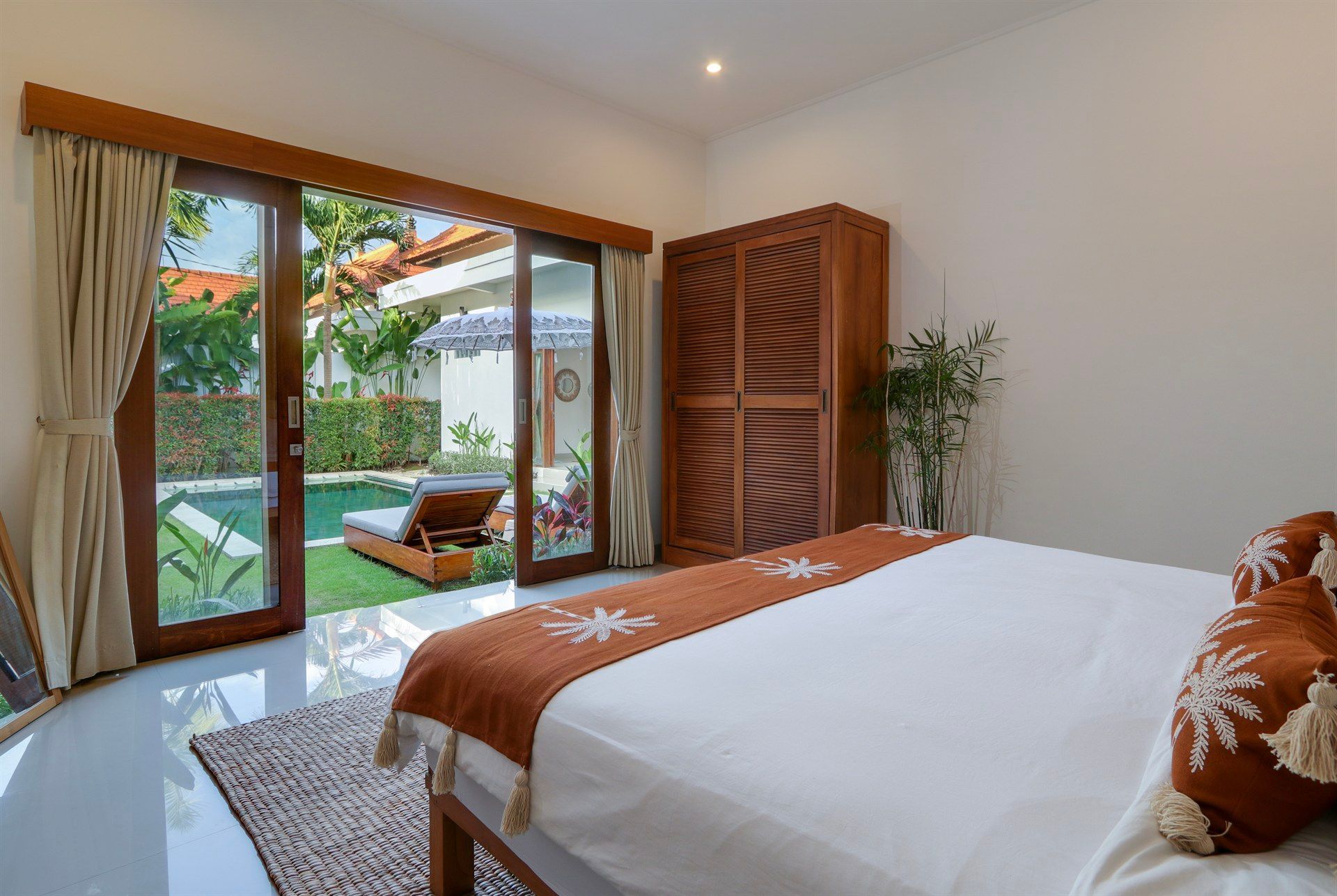 Bedroom with a bed, wooden wardrobe, and open doors to a pool.