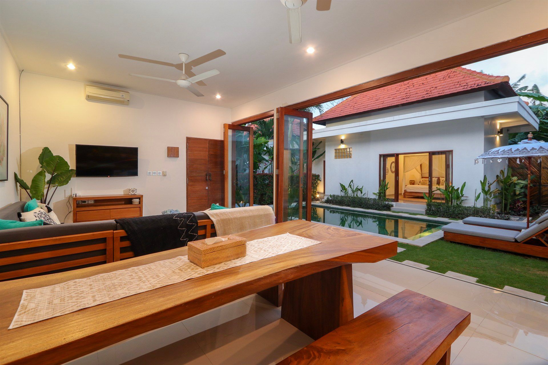 Open-plan living space with dining area, sofa, and view of pool and outdoor seating.