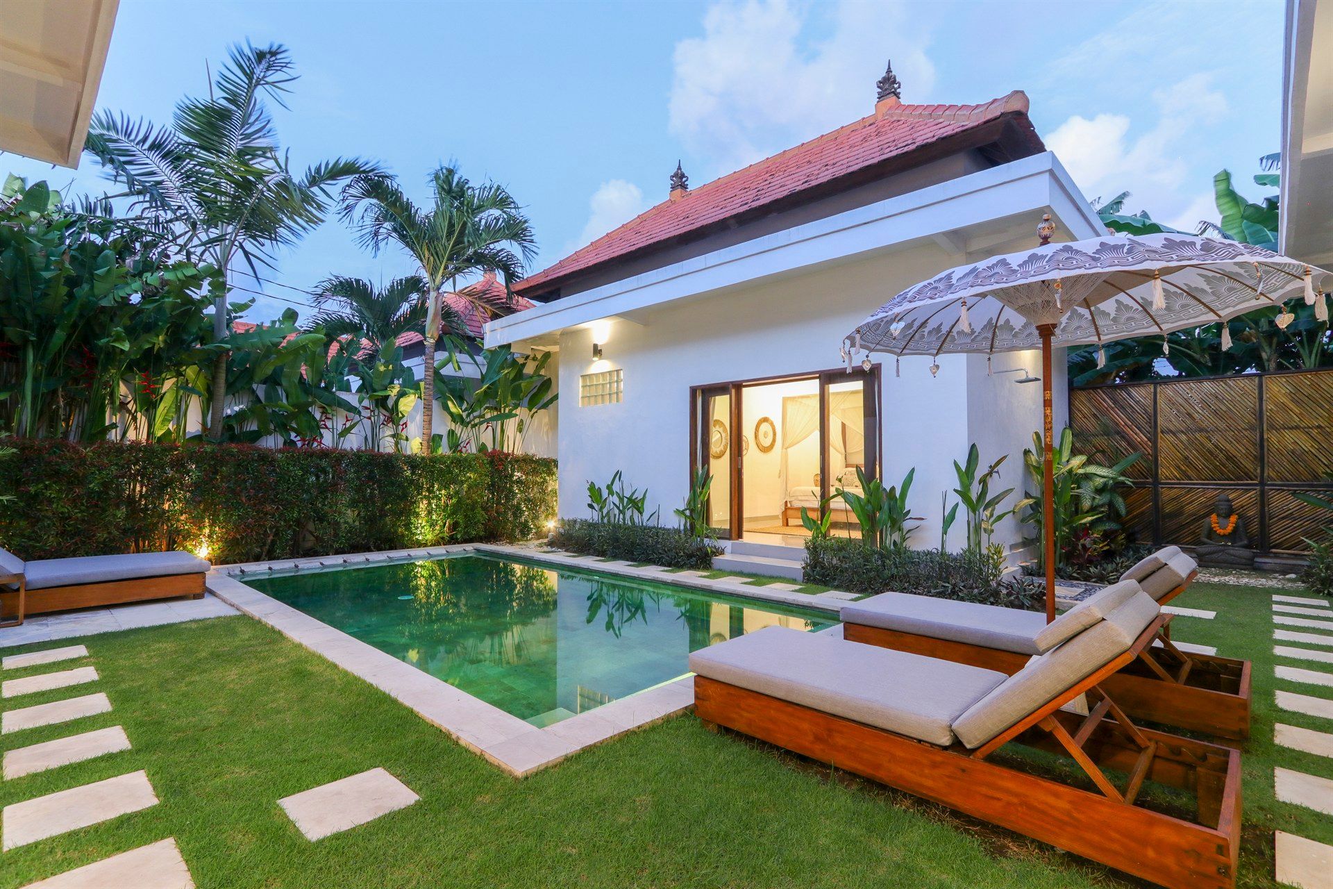 Poolside villa with pool, lounge chairs, and tropical landscaping.