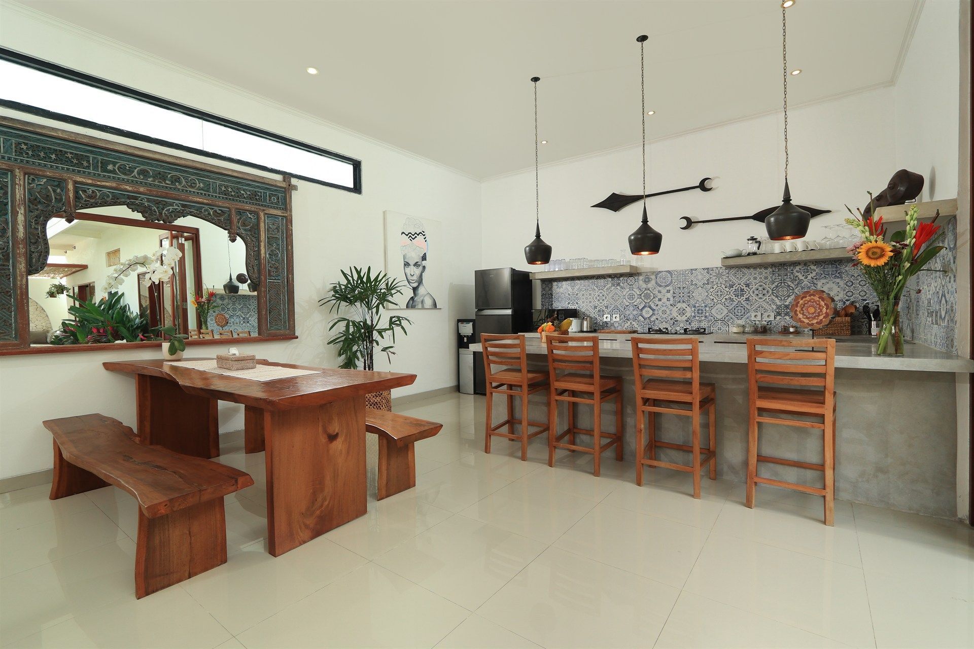 Kitchen with a wooden table, benches, and a bar with stools, contrasted by a patterned tile backsplash.