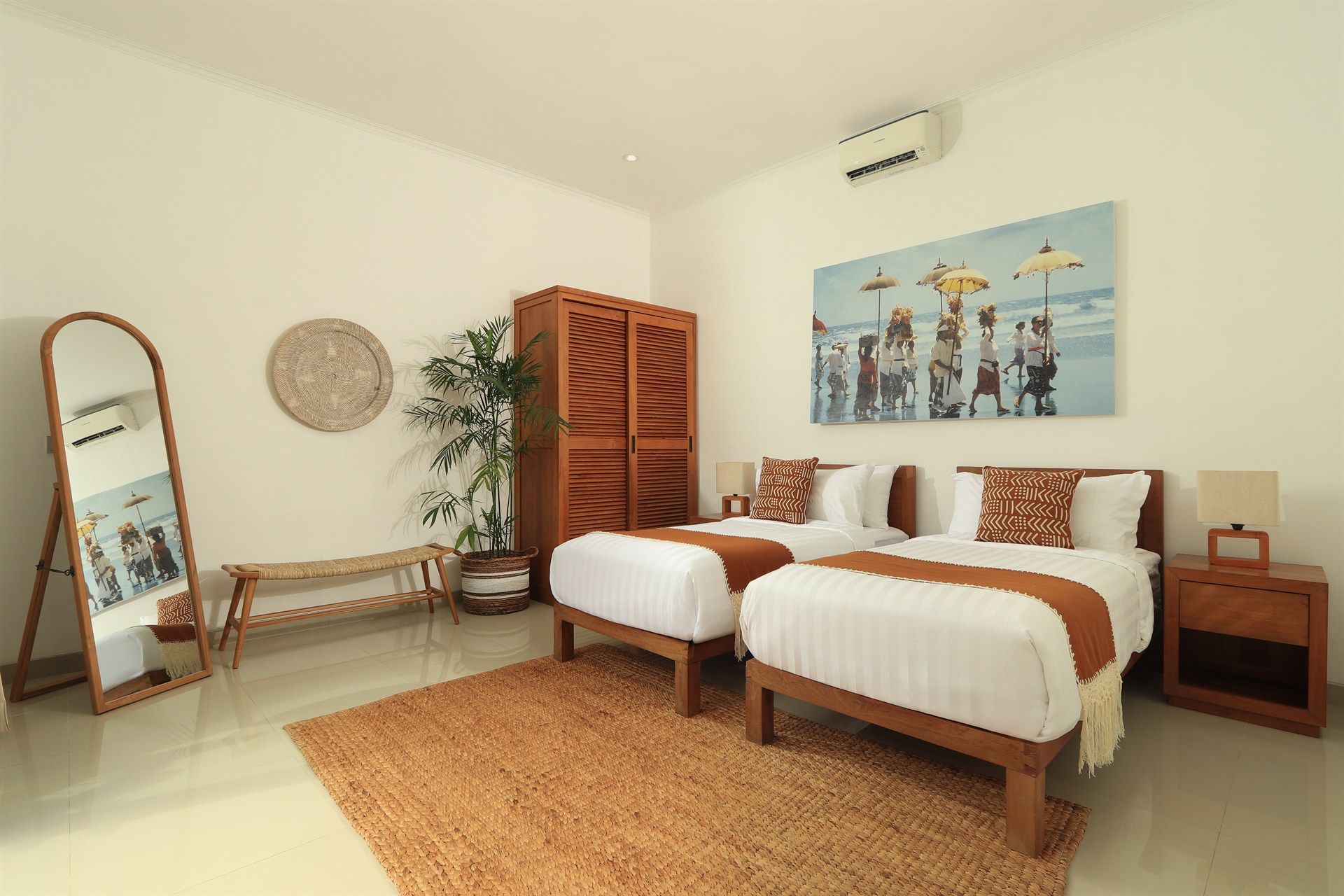 Bedroom with two twin beds, wooden furniture, artwork, and jute rug.