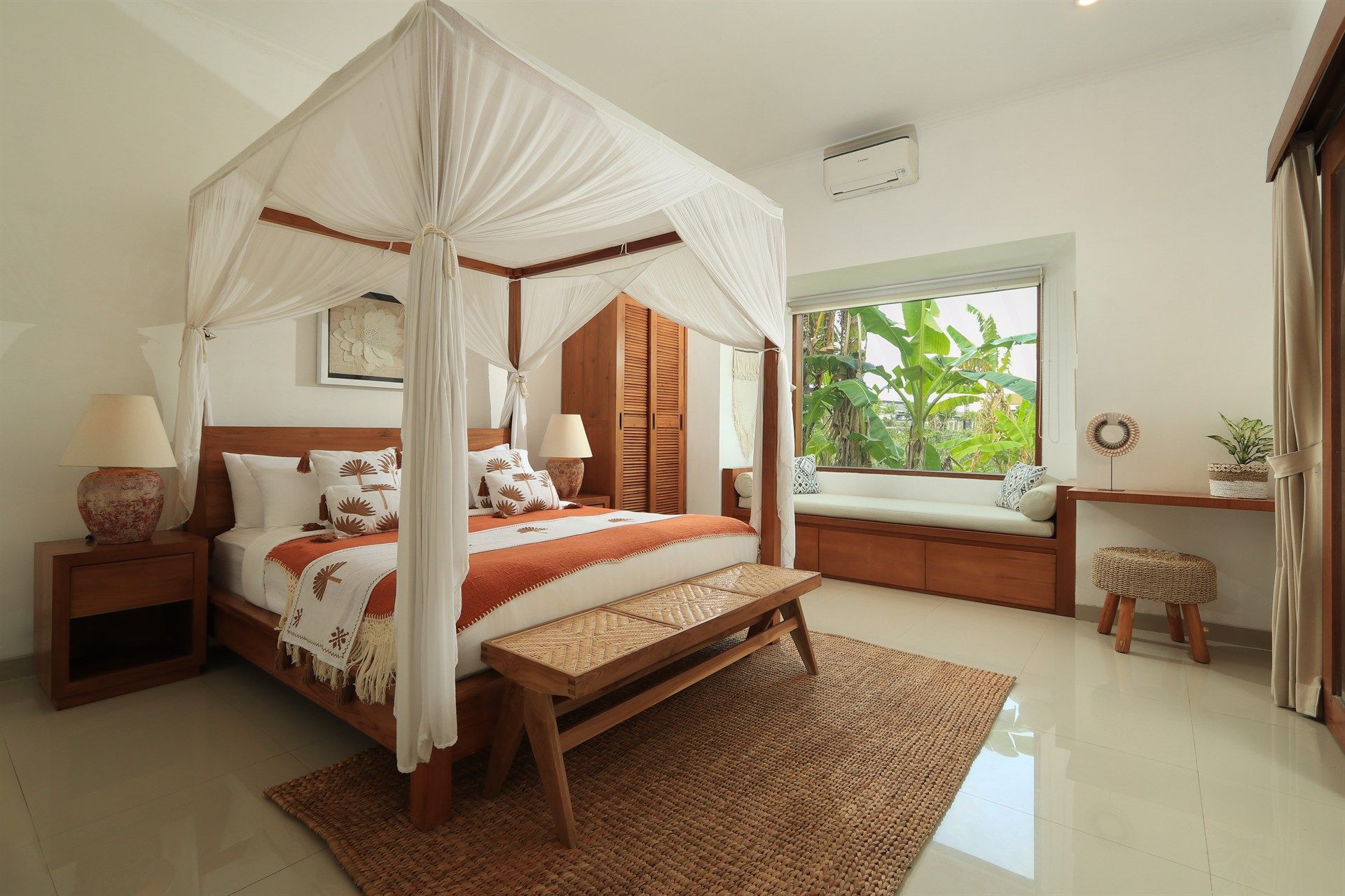 Bedroom with canopy bed, bench, window seat, wooden furniture, and neutral decor.